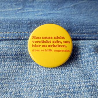 Ansteckbutton Man muss nicht verrückt sein um hier zu arbeiten. Aber es hilft ungemein. auf  Jeans